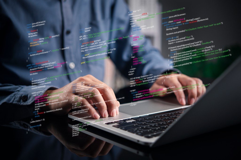 Manos sobre un teclado de laptop con código superpuesto: excelencia operacional TI
